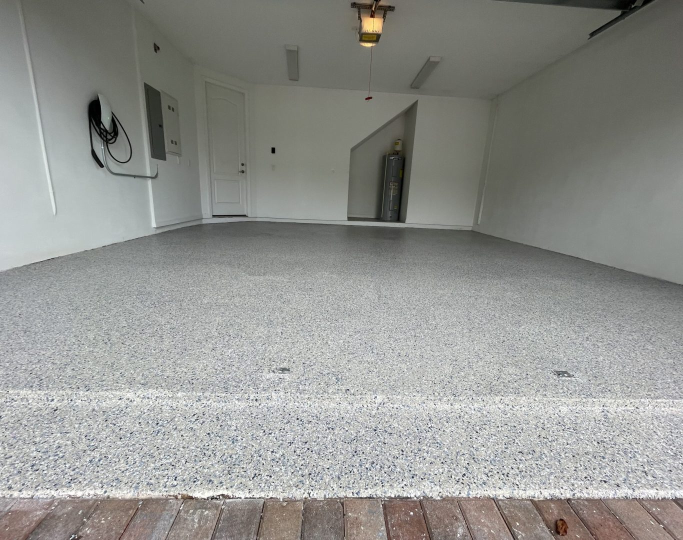 Technician applying polyaspartic coating to a residential garage floor in Palmetto Bay, FL